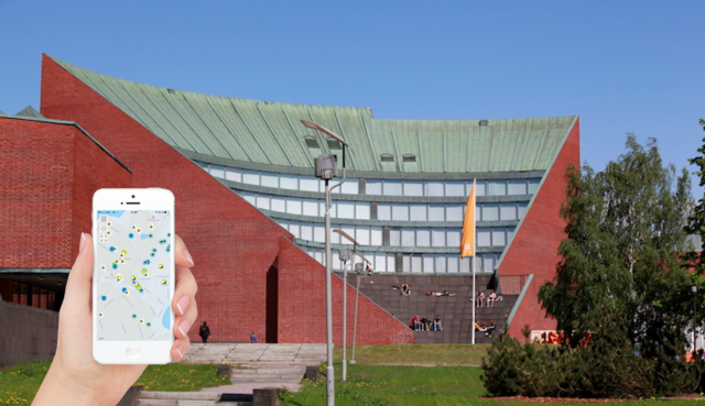 Campus tour app in use on a smart phone in front of Undergraduate Centre showing different places in Otaniemi..